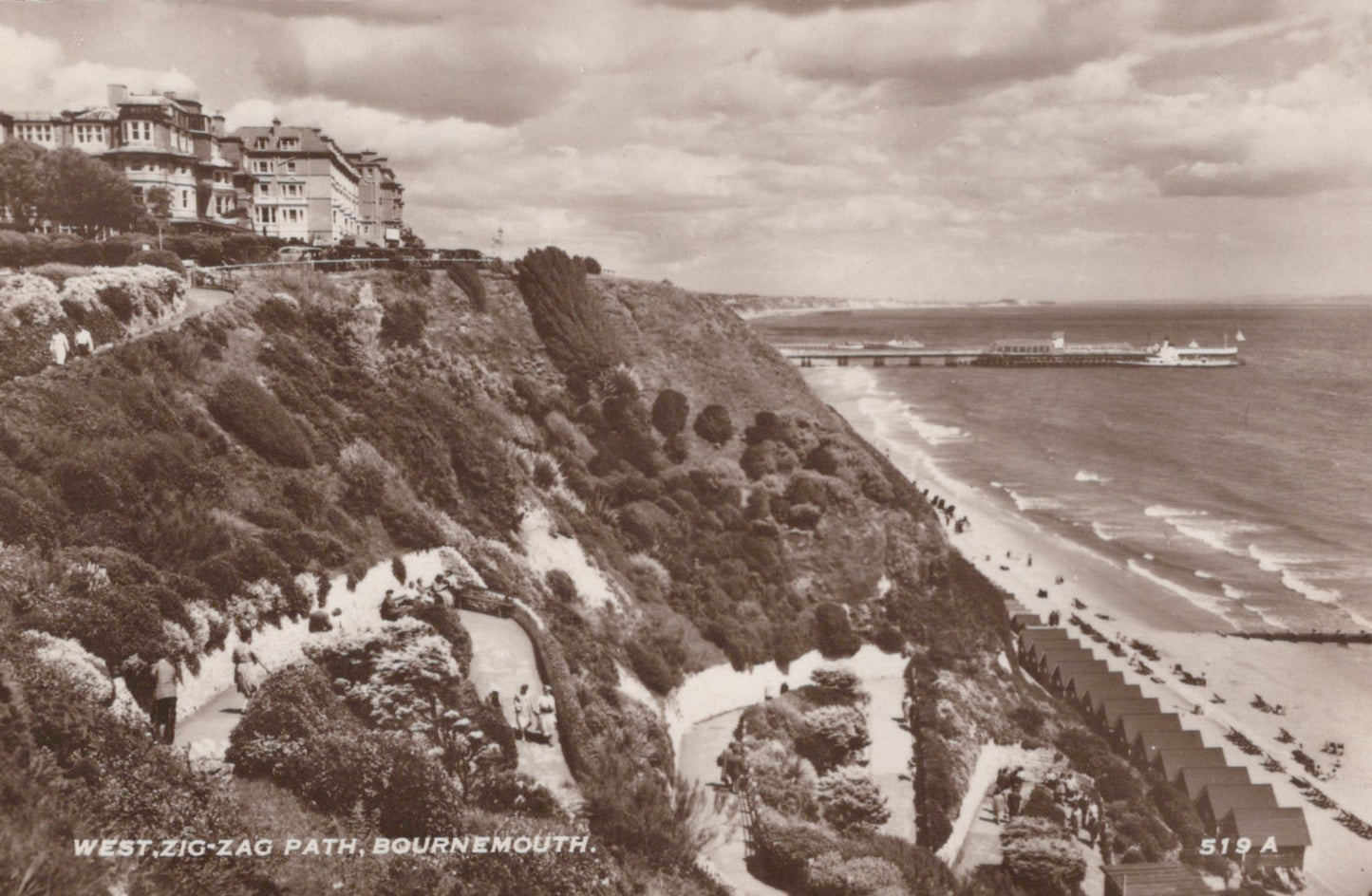 Vintage black and white photograph of a coastal scene with a zigzag path, houses, and a beach.