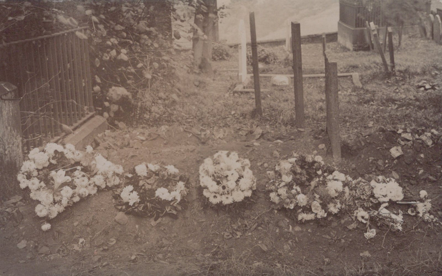 Vintage black and white photo of a cemetery with floral wreaths and gravestones.