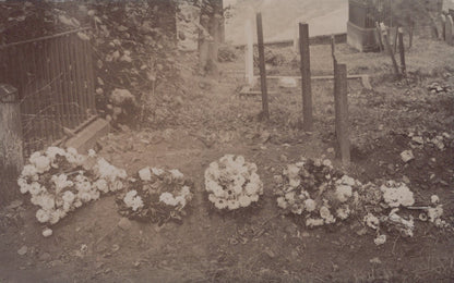Vintage black and white photo of a cemetery with floral wreaths and gravestones.