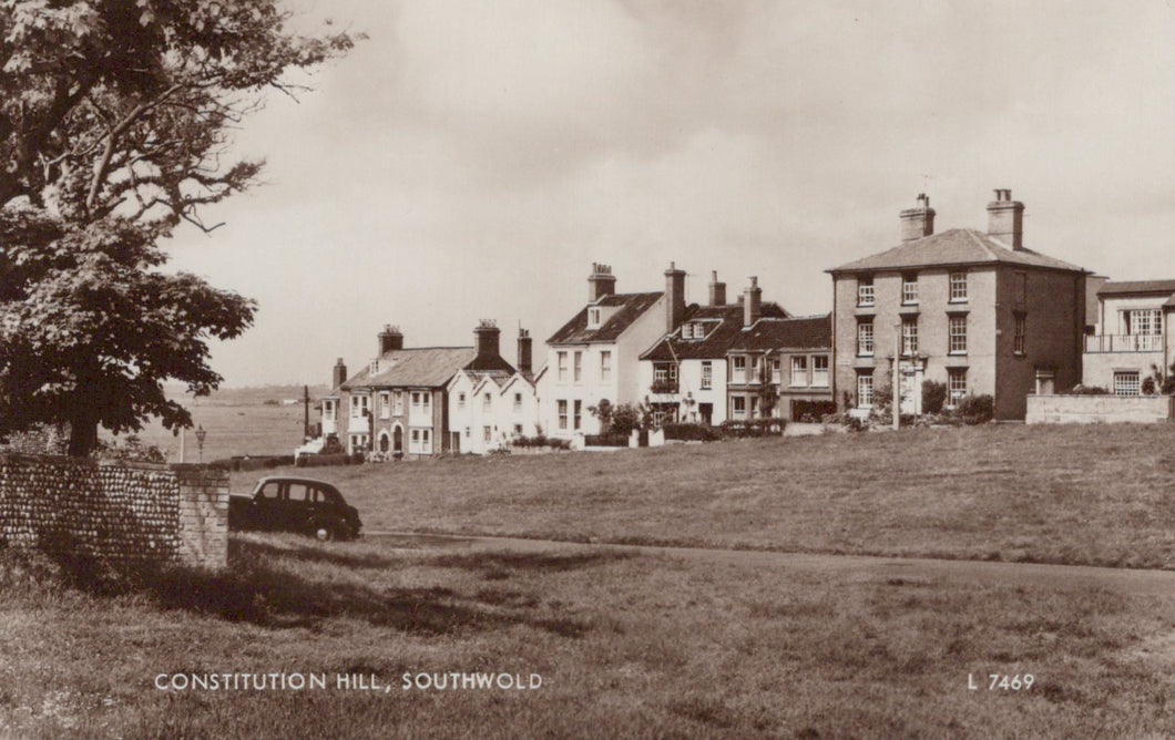 Vintage black and white photo of a village scene with houses and a car on Constitution Hill, Southwold.