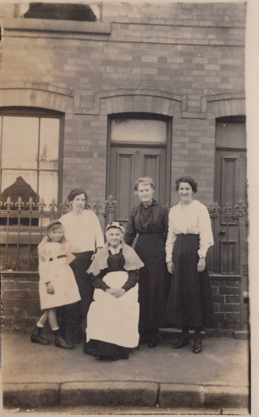 Group of women and a child posing in front of a brick building