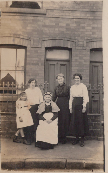 Group of women and a child posing in front of a brick building