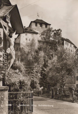 Vintage black and white photo of a castle with a crucifix on a stone wall.