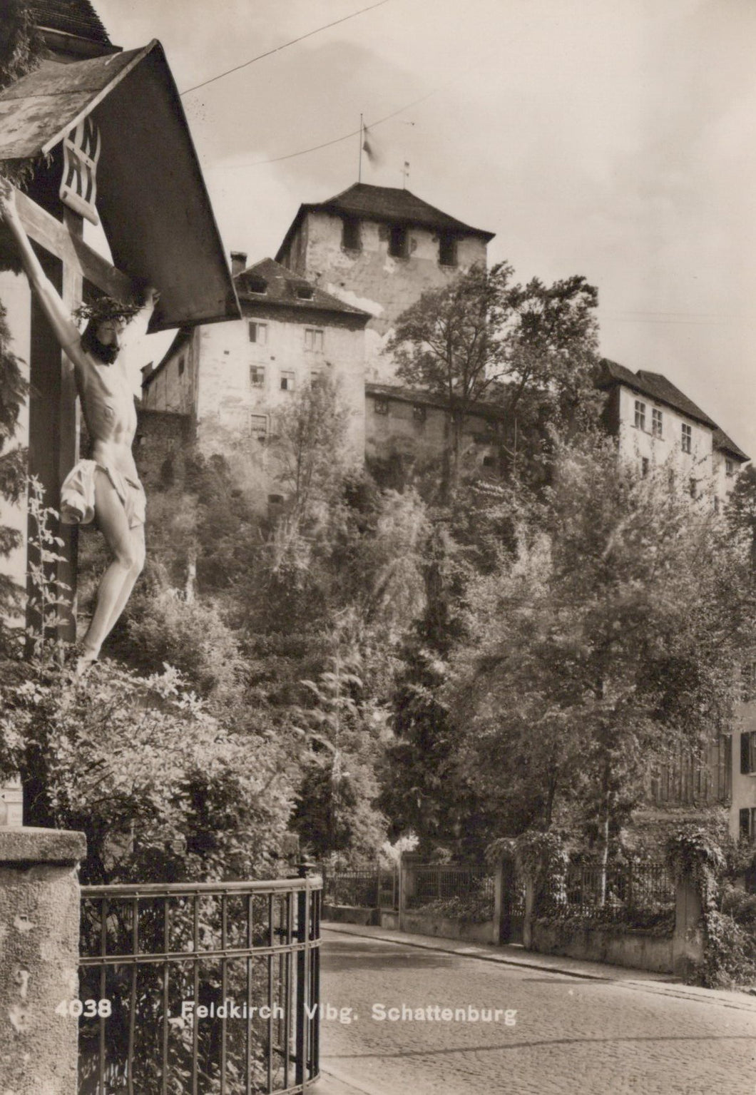 Vintage black and white photo of a castle with a crucifix on a stone wall.