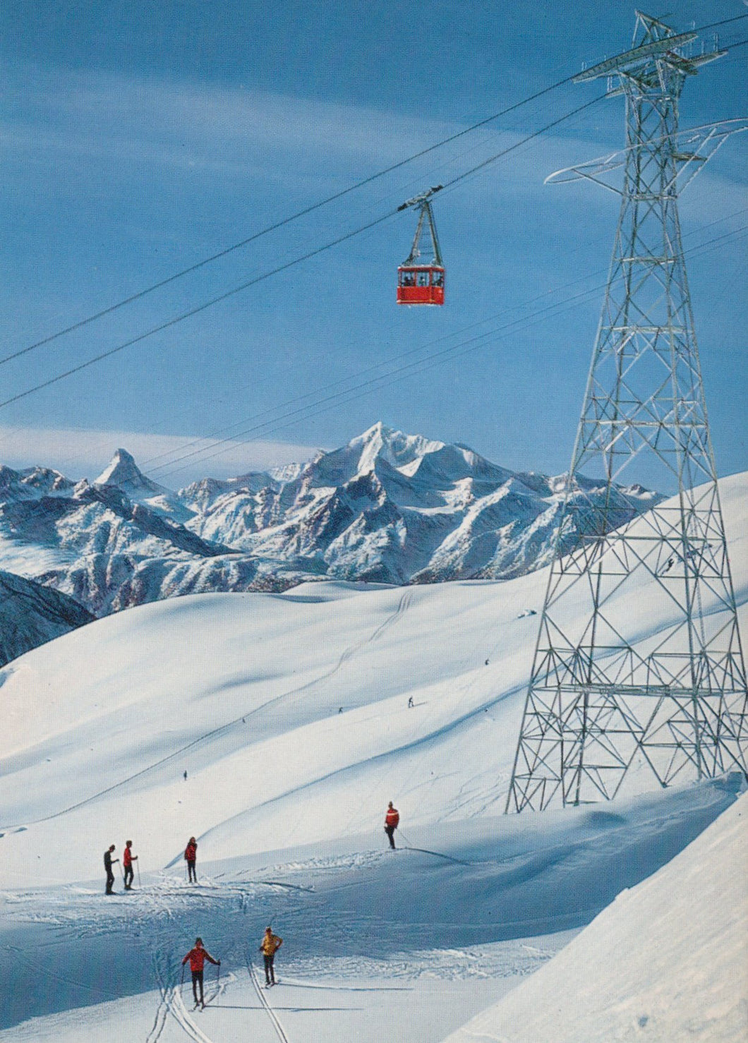 Ski lift with skiers on a snowy mountain landscape under a clear blue sky.