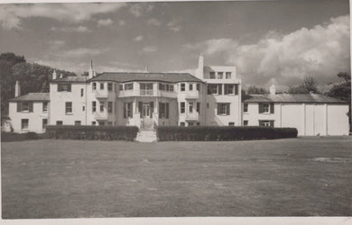 Black and white photo of a large building with a grassy area in front