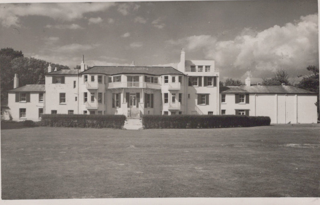 Black and white photo of a large building with a grassy area in front