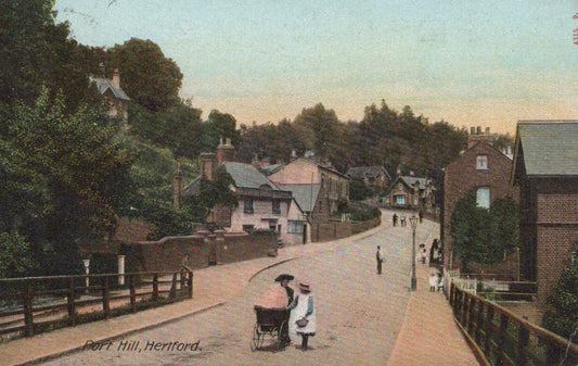 Vintage postcard of a street scene with people and a baby carriage in a residential area.