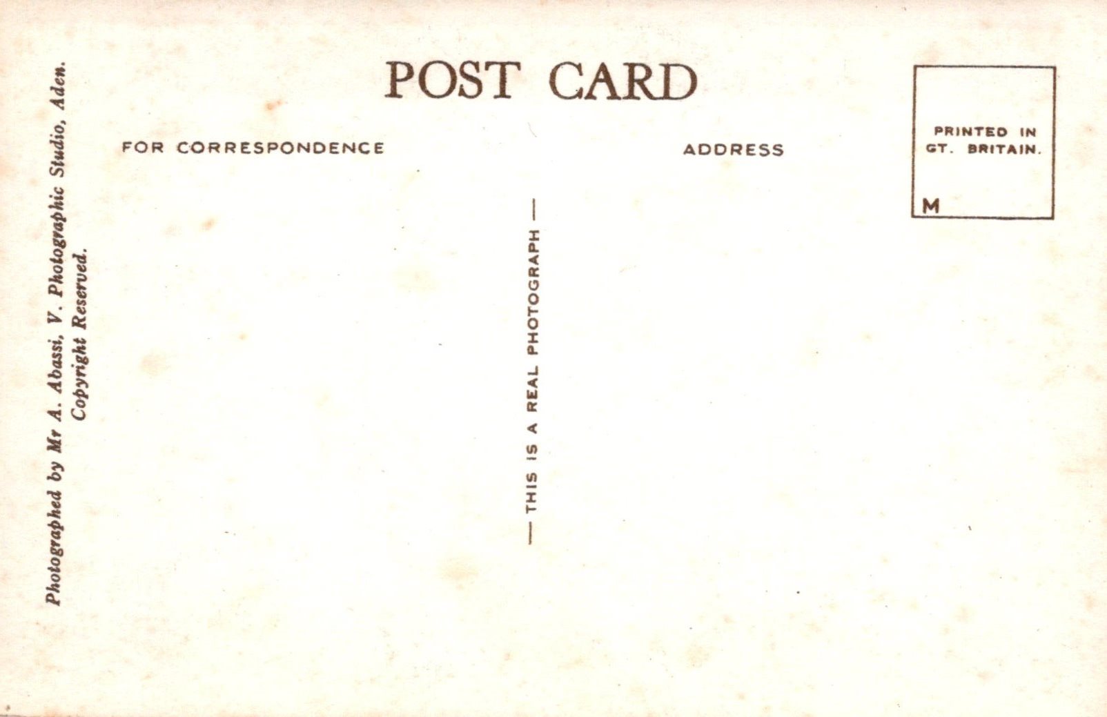 Back of a postcard with text and a small square logo on a beige background