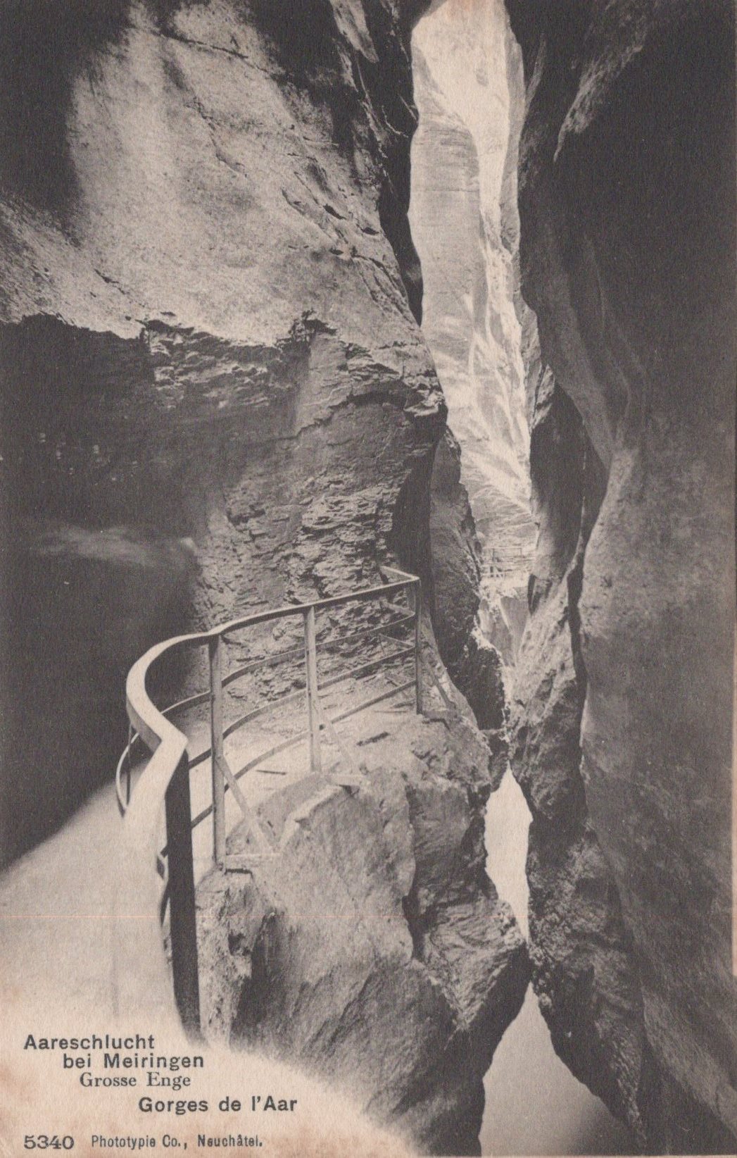 Narrow gorge with a metal staircase between two rocky walls, vintage photograph.
