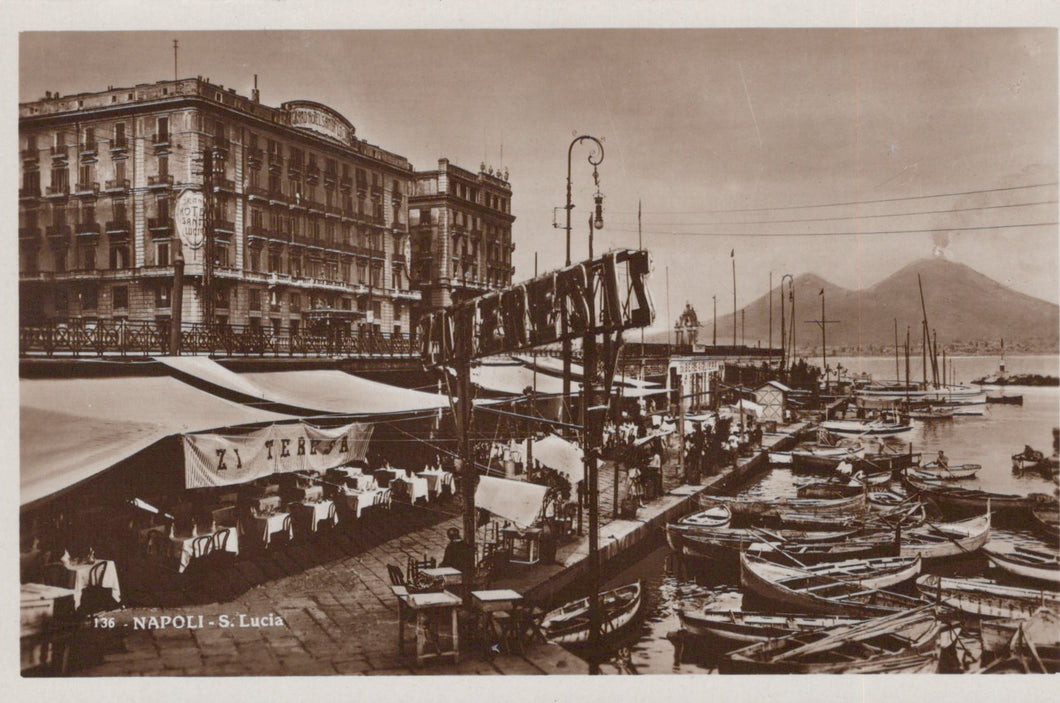 Vintage photograph of a waterfront scene with boats and buildings, featuring a large sign.