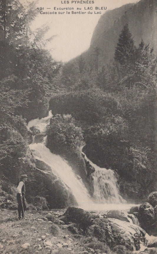 Vintage photograph of a waterfall in a mountainous area with a person standing nearby.
