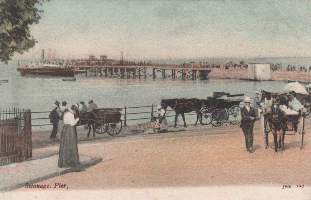 Vintage postcard of Swanage Pier with people and horse-drawn carriages.