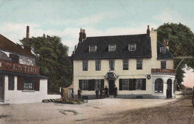 Vintage postcard of a pub with people outside, surrounded by trees and other buildings.