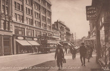 Load image into Gallery viewer, Vintage black and white photograph of a city street with pedestrians and shops in Cardiff.
