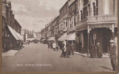 Vintage black and white photograph of a street scene in Porthcawl, featuring people and shops.