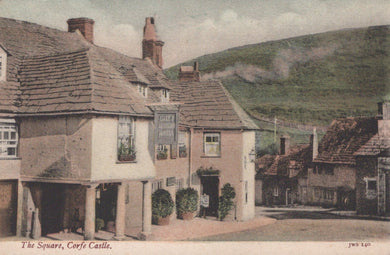 Vintage postcard of a village square with houses and a sign, featuring a steam train in the background.