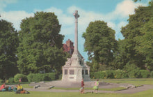 Load image into Gallery viewer, Memorial monument in a park with people around, trees in the background
