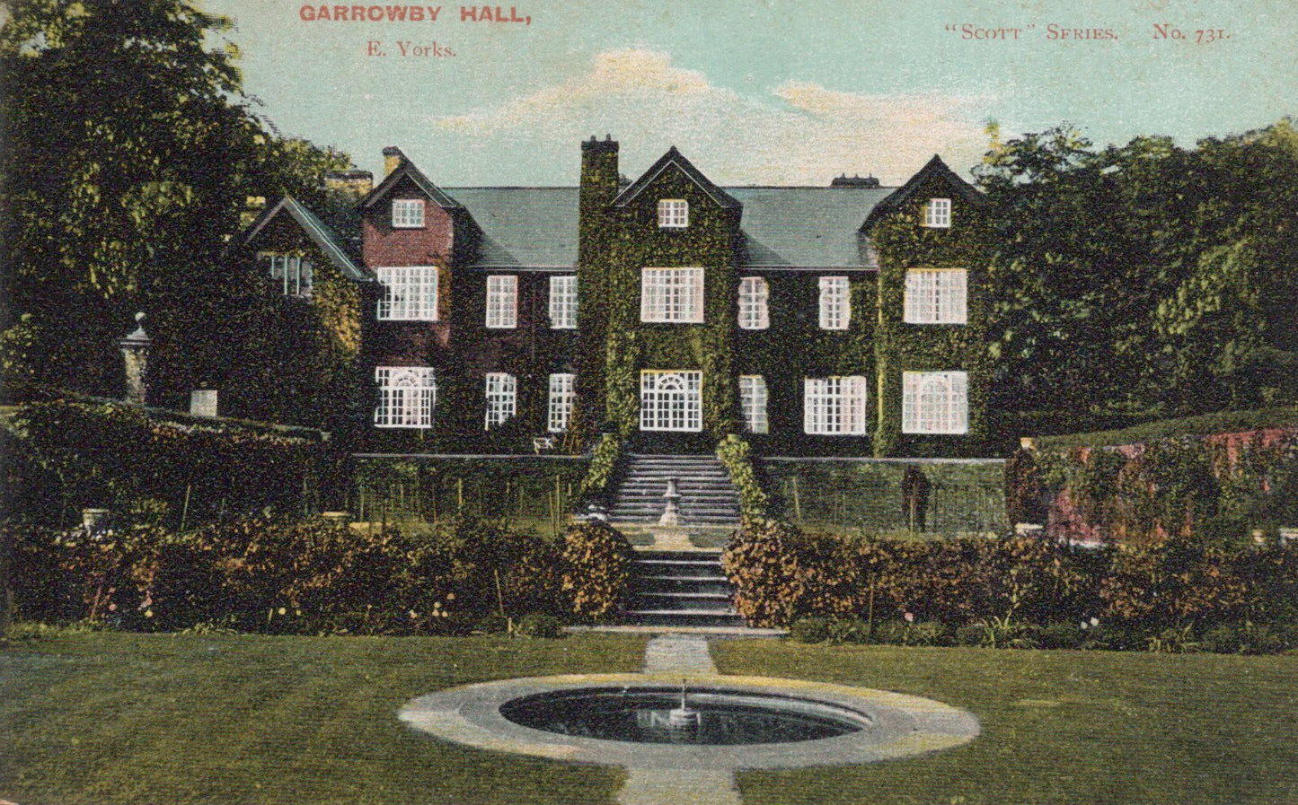 Historic mansion with a fountain in front, surrounded by trees and greenery.