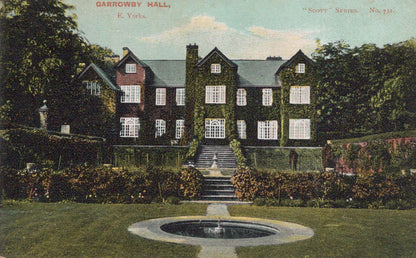 Historic mansion with a fountain in front, surrounded by trees and greenery.