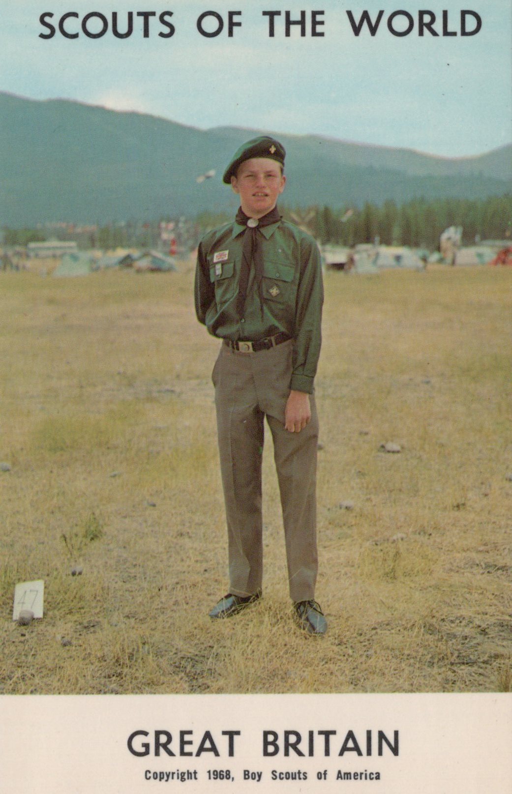 Scout in uniform standing in a field with mountains in the background, labeled 'Scouts of the World, Great Britain'.