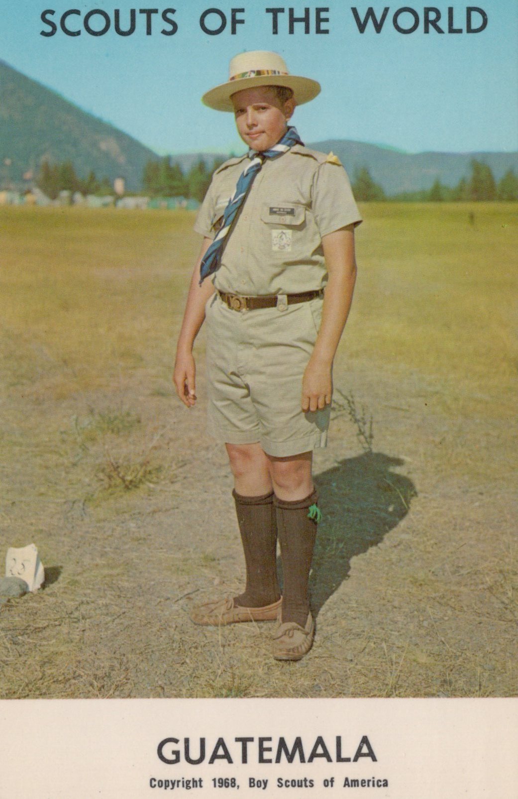 Scout in uniform standing outdoors with mountains in the background, labeled 'Scouts of the World Guatemala'.