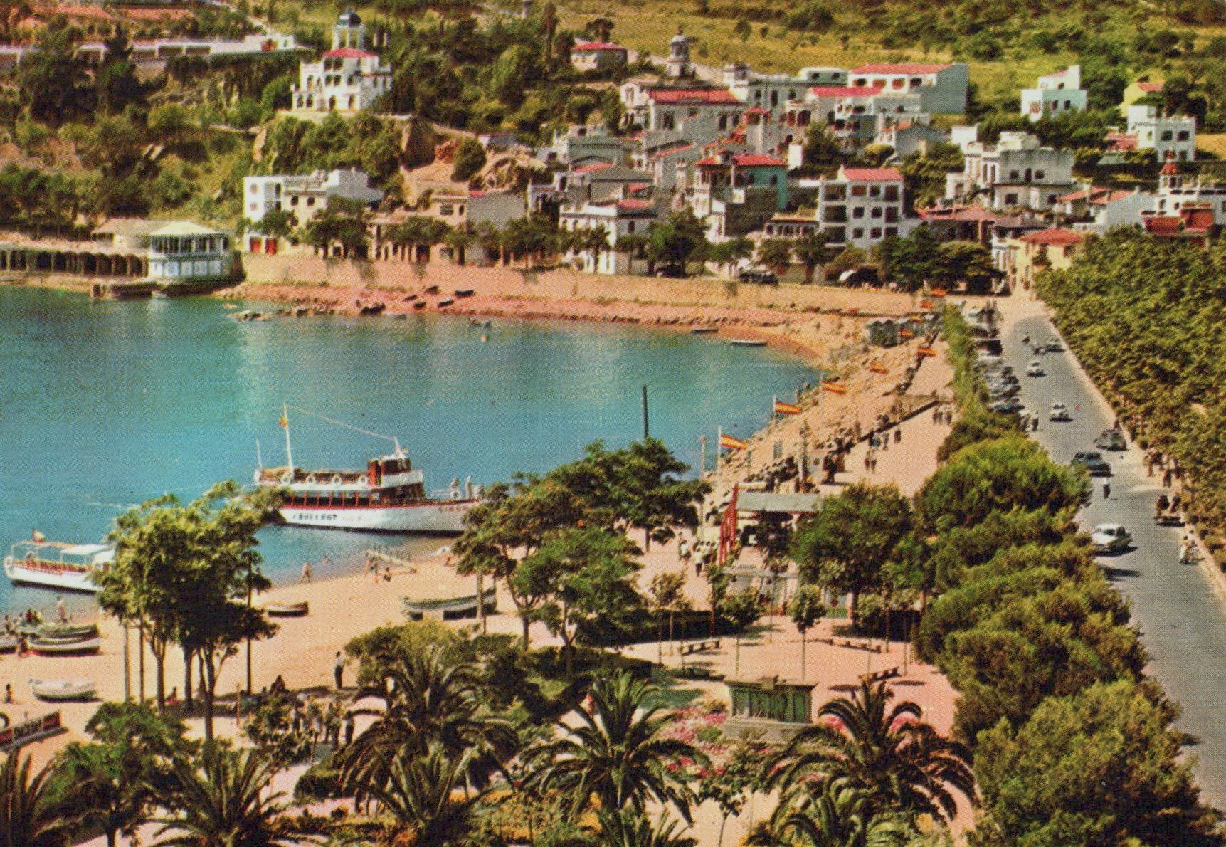 Coastal town with a harbor and beach, featuring buildings and a boat.