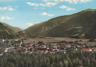 Vintage-style image of a town nestled between mountains with a clear blue sky.