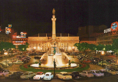 Famous landmark at night with fountain and surrounding cars, illuminated by streetlights.