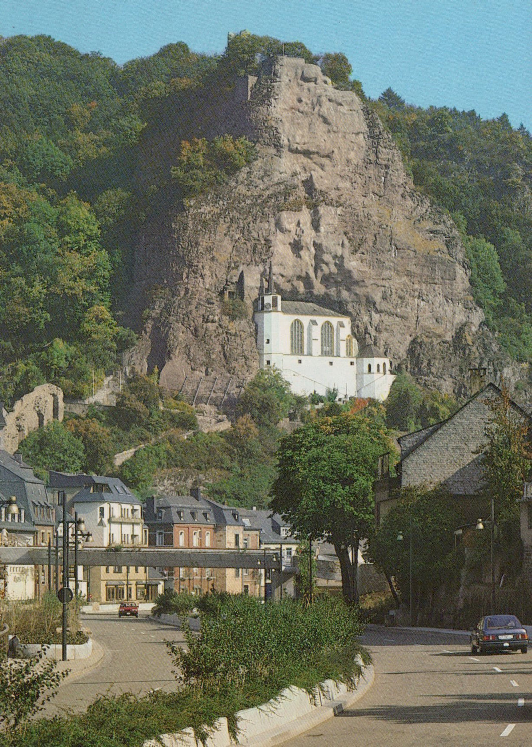 Ruin of a castle on a rocky outcrop with a town below in Luxembourg