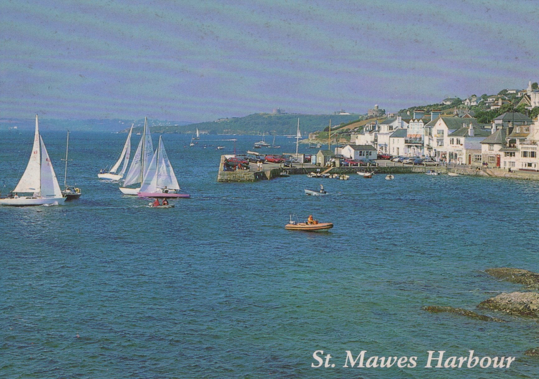 Sailing boats in St. Mawes Harbour with buildings on a hillside.