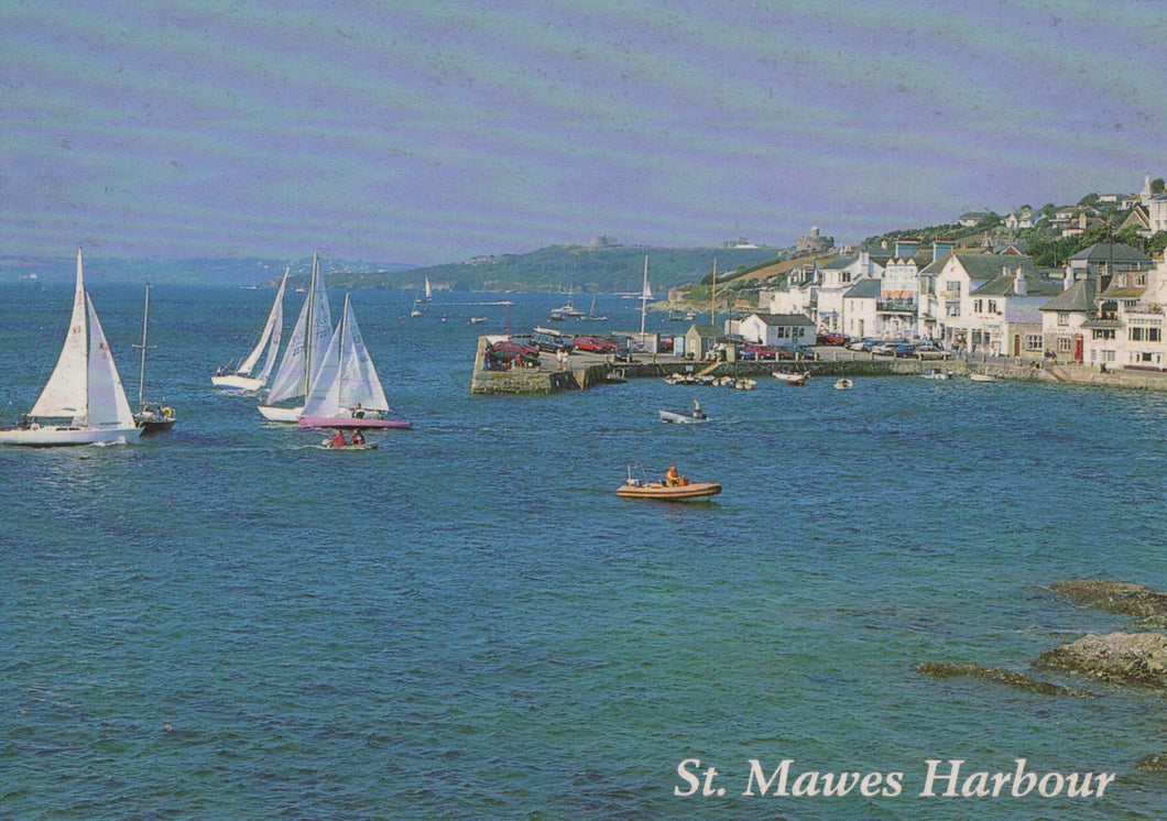 Sailing boats in St. Mawes Harbour with buildings on a hillside.