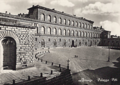 Historical black and white photo of a large stone building with arched entrance.