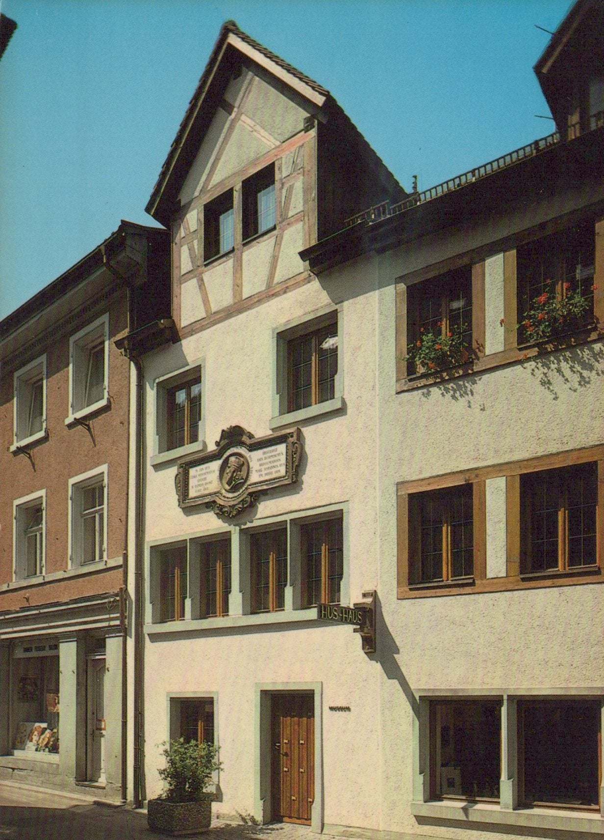 Traditional European building with wooden shutters and a decorative plaque on a street.