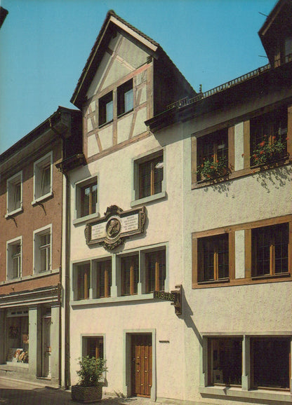 Traditional European building with wooden shutters and a decorative plaque on a street.