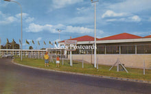 Load image into Gallery viewer, Two children standing on a sidewalk with a building and flags in the background 
