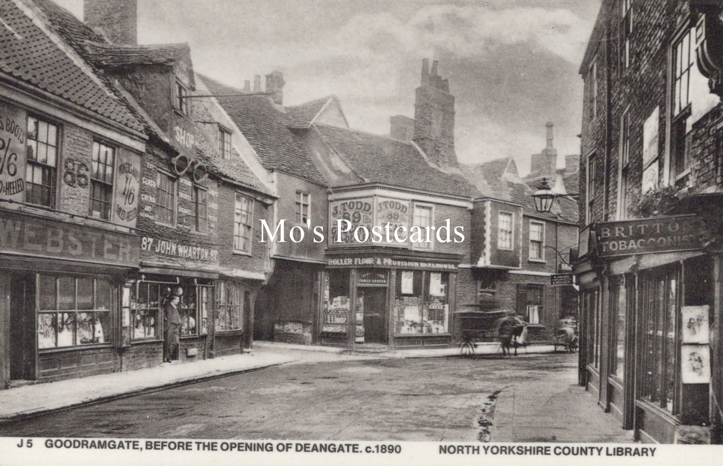 Vintage black and white photo of a street scene with shops and pedestrians 