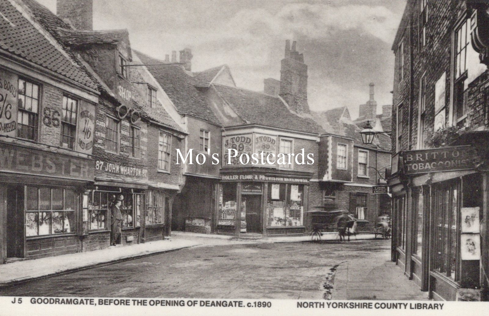 Vintage black and white photo of a street scene with shops and pedestrians 