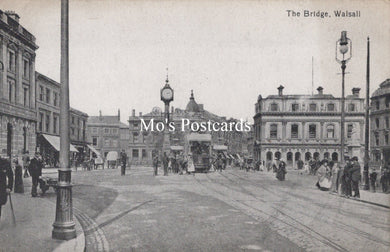 Vintage black and white photo of a town square with people, buildings, and a clock tower.