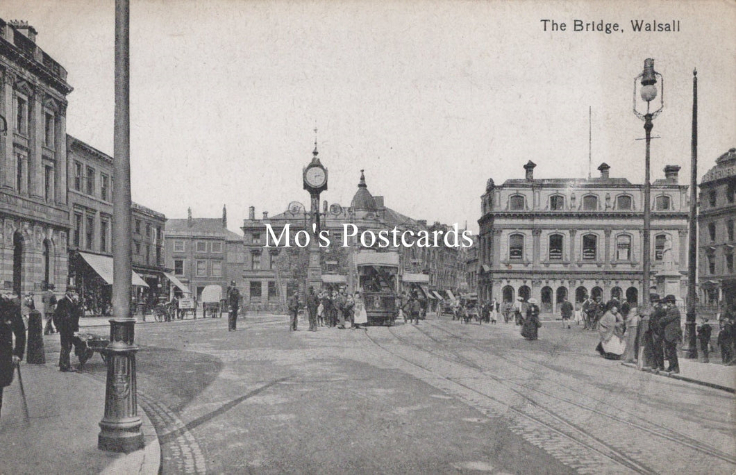 Vintage black and white photo of a town square with people, buildings, and a clock tower.