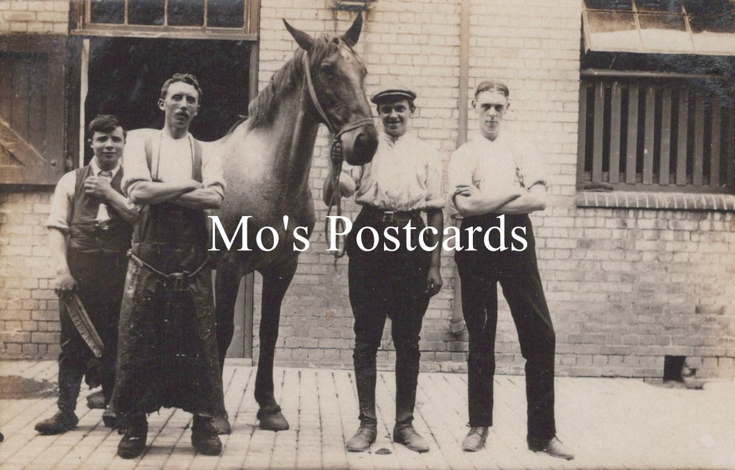Vintage black and white photo of four men with a horse in front of a brick building 