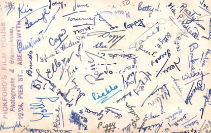Sheet of paper with various handwritten signatures in blue ink on a beige background.