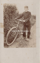 Load image into Gallery viewer, Vintage photograph of post delivery boy with a bicycle on a path with foliage.
