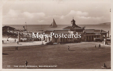 Vintage black and white postcard of a pier approach with a sailboat and buildings.