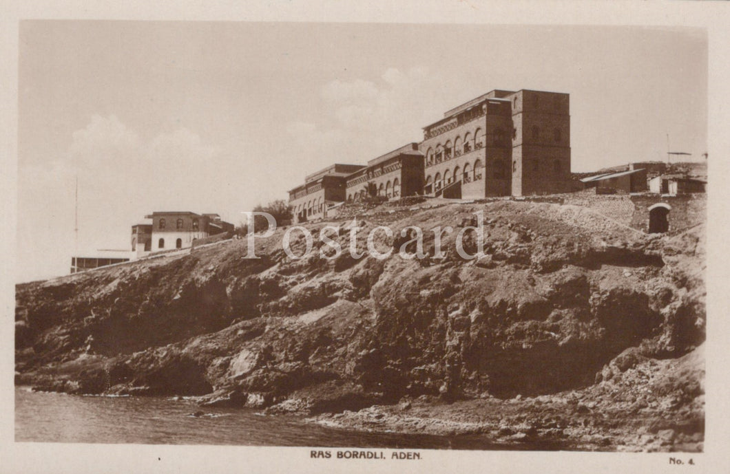 Vintage black and white postcard of a coastal scene with buildings on a cliff.