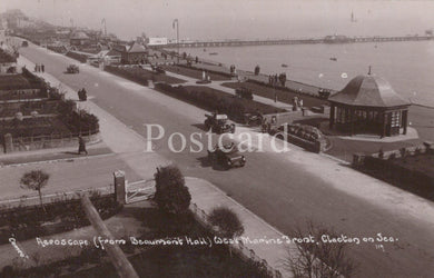 Vintage black and white postcard of a coastal scene with roads, buildings, and vehicles.