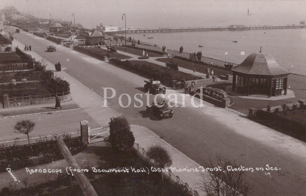 Vintage black and white postcard of a coastal scene with roads, buildings, and vehicles.