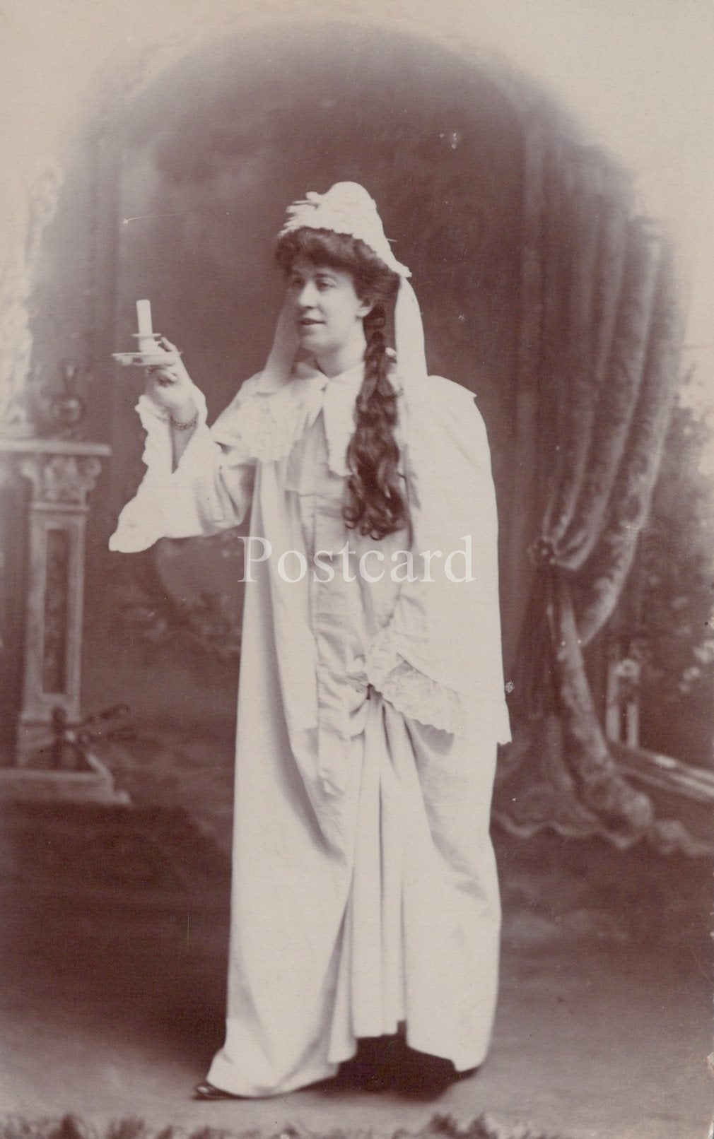 Vintage photograph of a woman in a white dress with a veil, holding a cigarette, on a postcard.