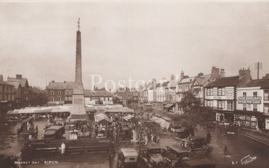 Vintage black and white photo of a town square with a central obelisk and market stalls.