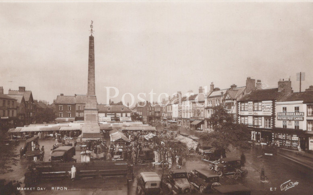 Vintage black and white photo of a town square with a central obelisk and market stalls.